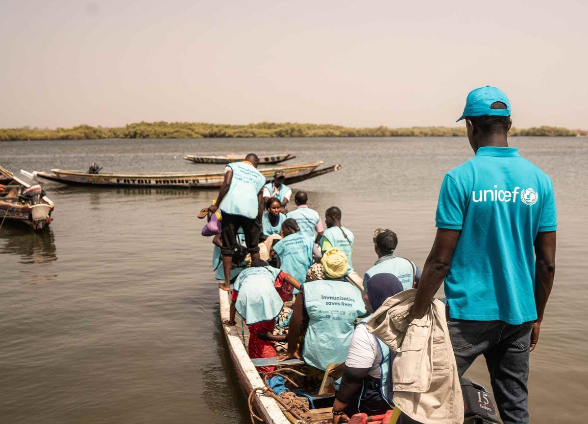 Health care workers board a boat to bring life-saving polio vaccines to children on Jinak Island, The Gambia