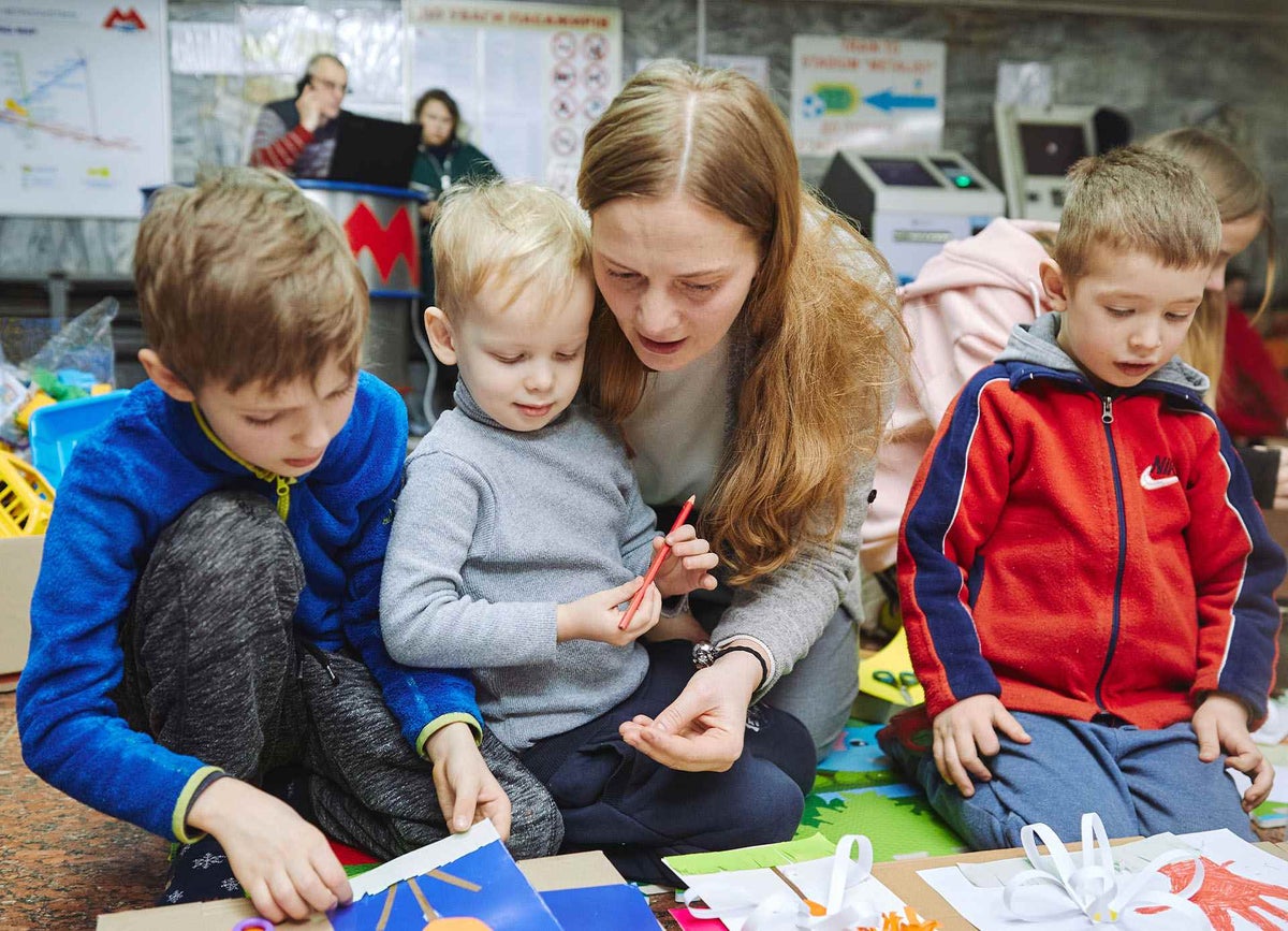 Volunteer plays with children at makeshift care centre in train station