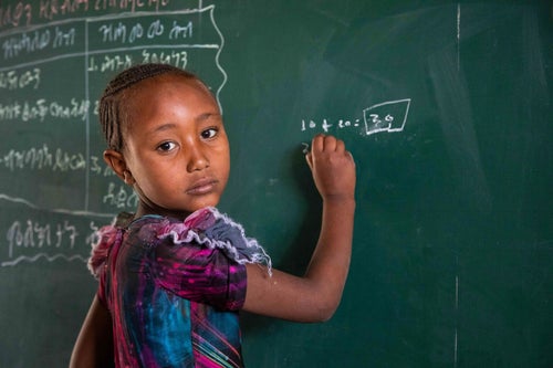 A girl writes and equation on a chalkboard.