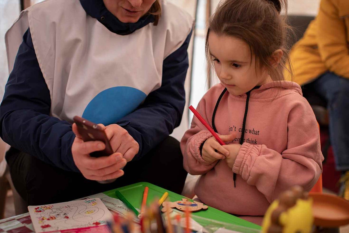 A child therapist plays with Dasha, four, inside a tent at a UNICEF-supported Blue Dot centre near the border crossing in Moldova. 