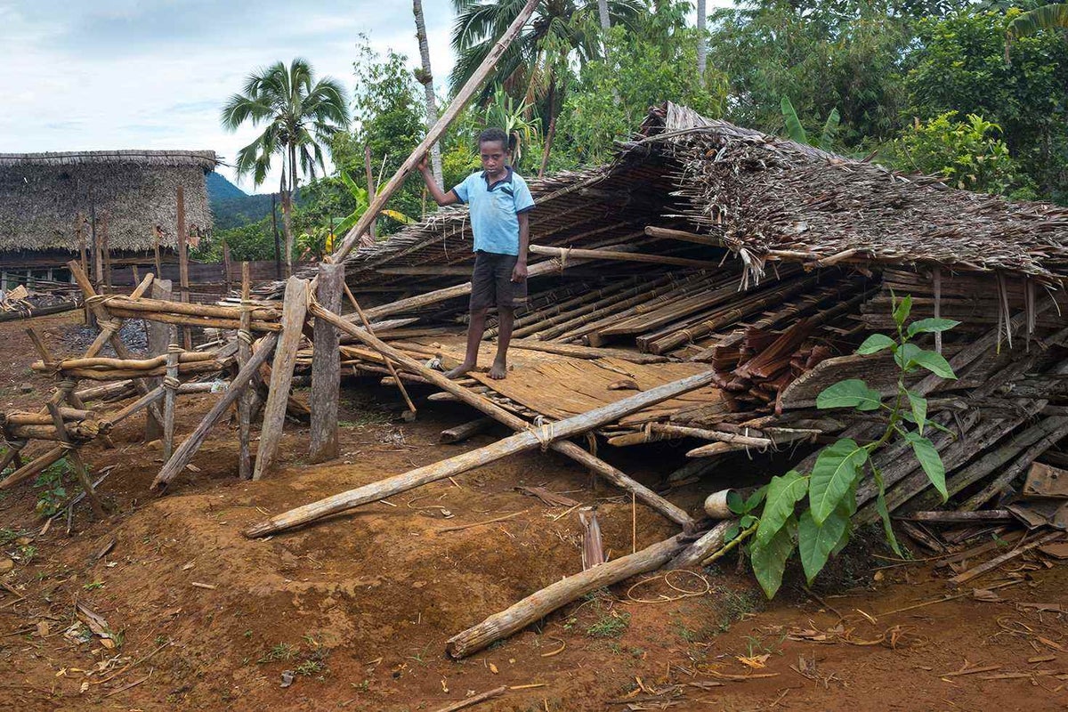 boy standing on hut destroyed by earthquake