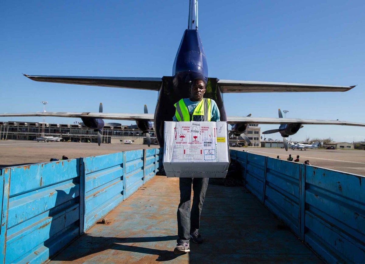 Man carries box of vaccines from plane.