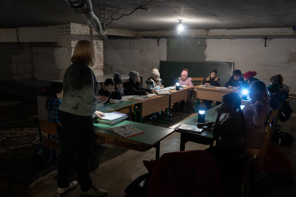 School children having a lesson in the basement with torches for light during the Ukraine War.