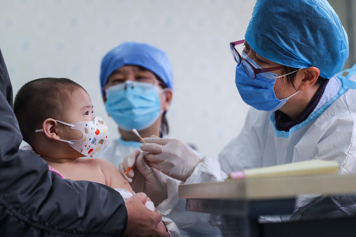 A health worker is vaccinating a baby. They are both wearing masks.