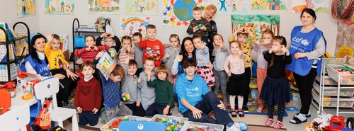 A bright, cheery room of young children smiling at the camera