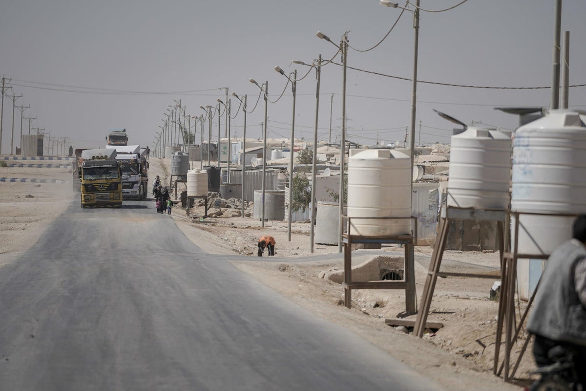 A road with trucks, and operating water tanks on the side of the road