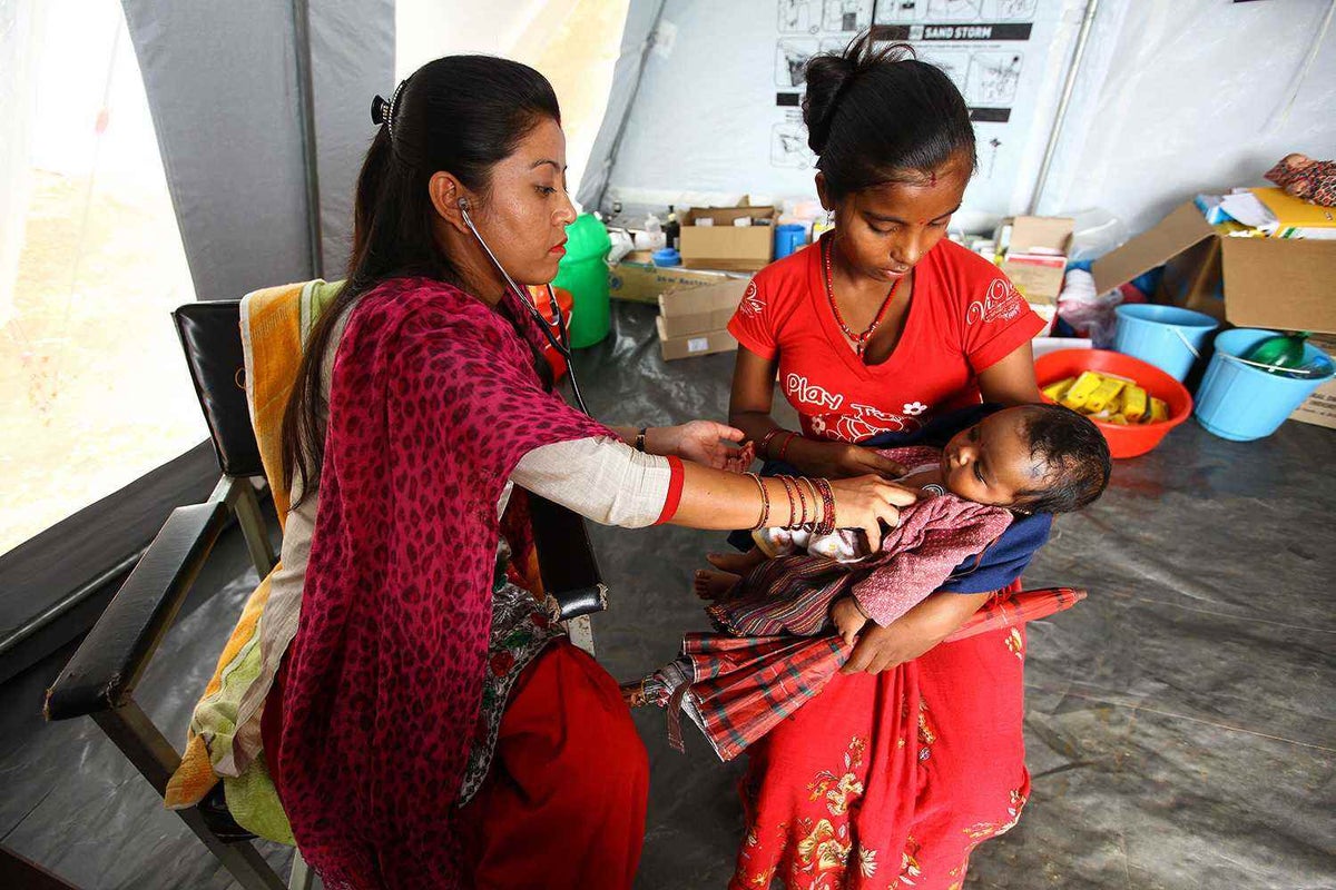 Rojina and her son Bhukumpa with an Auxiliary Midwife/Nurse at the UNICEF supported medical tent, which was built near the heavily damaged Nalang Health Post, in Nalang VDC of Dhading District.