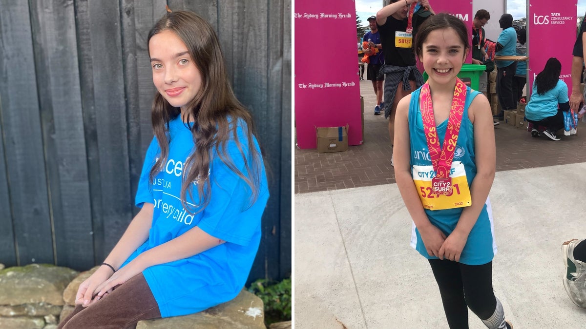 A young smiling girl stands at the finish line. 