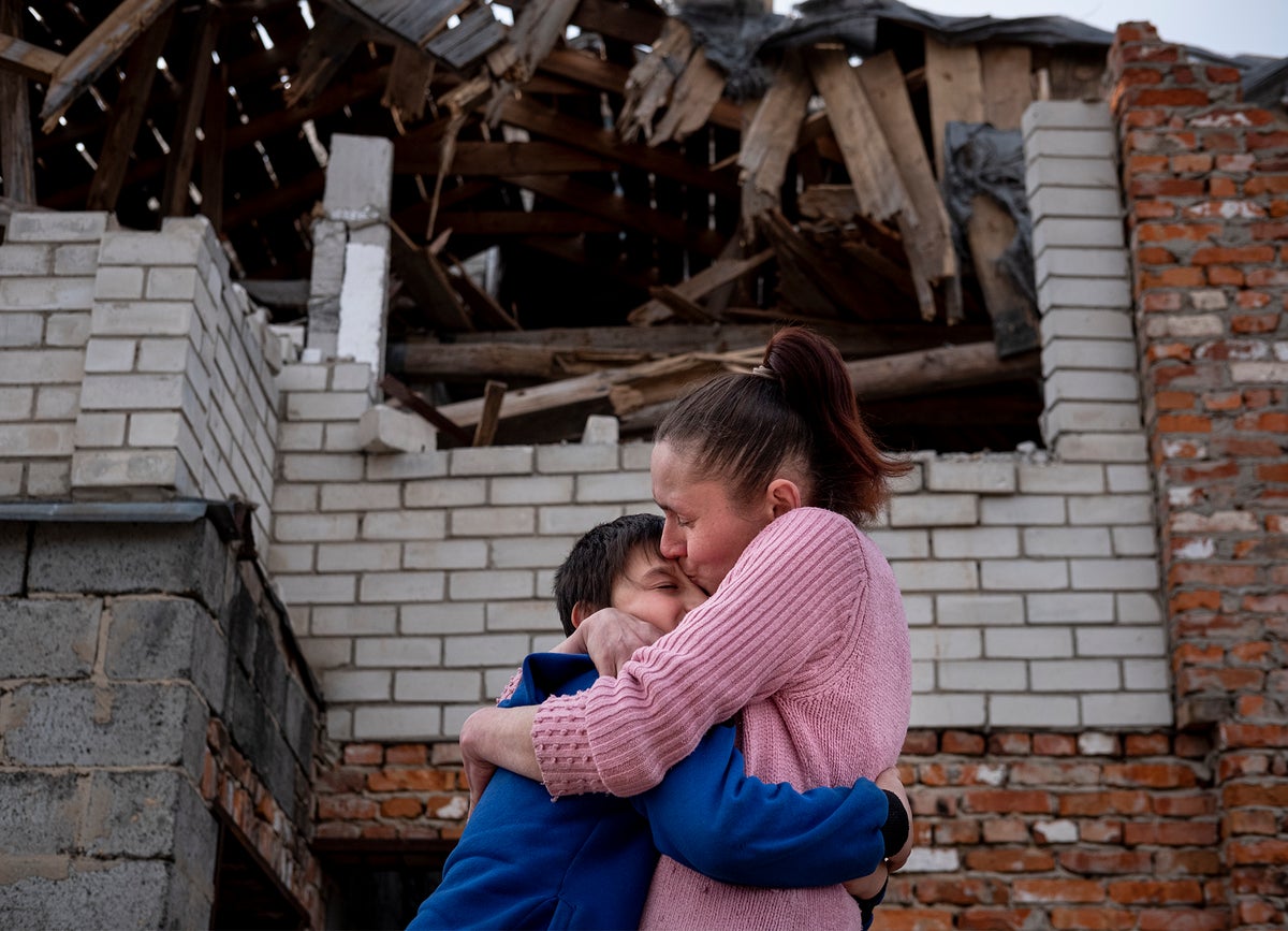 Olena holds her son, Mikhailo in a tight embrace in front of their home in Ukraine, damaged by conflict in the region. The mother and son were reunited with support from UNICEF after a month apart.