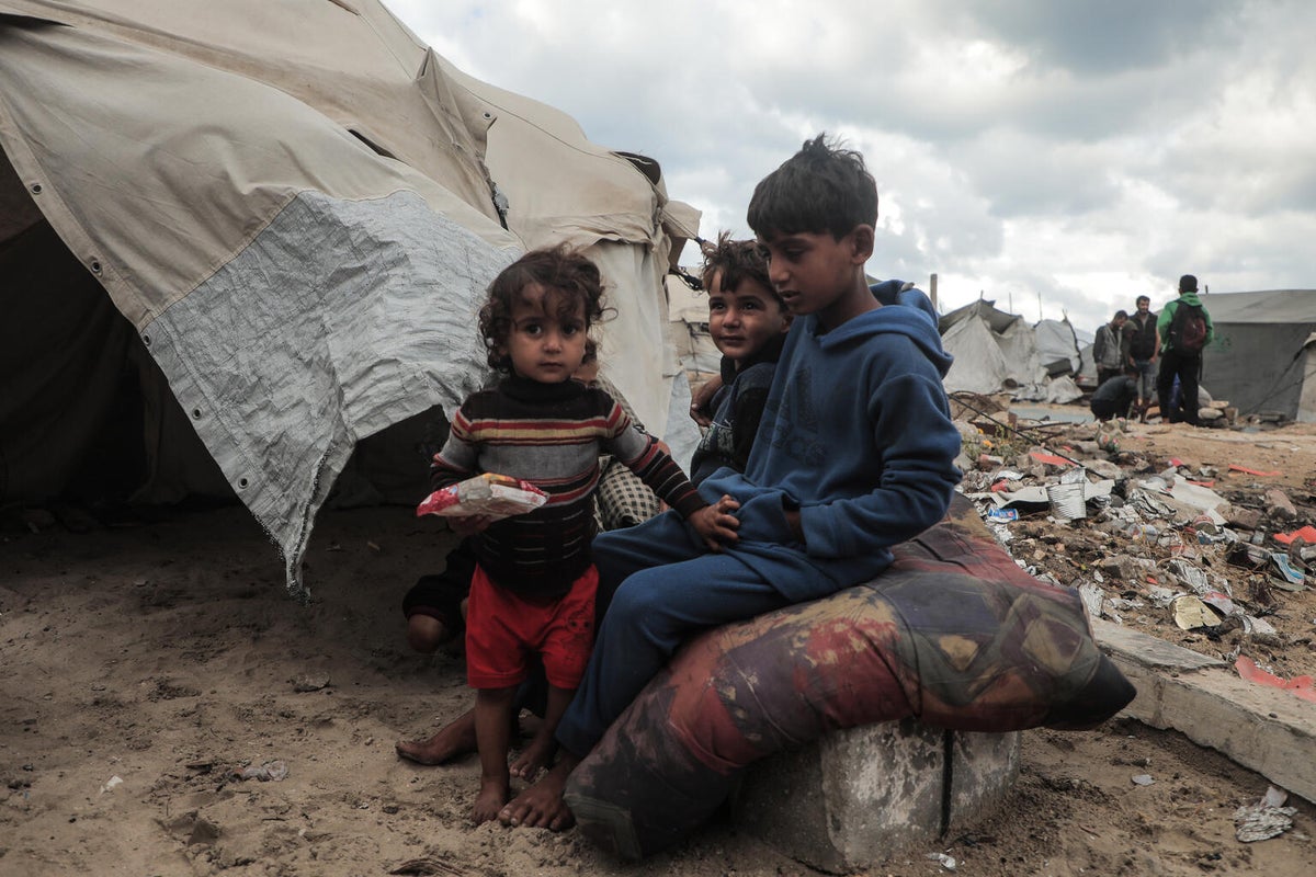 Three of Maysaa’s six children sit outside their temporary shelter