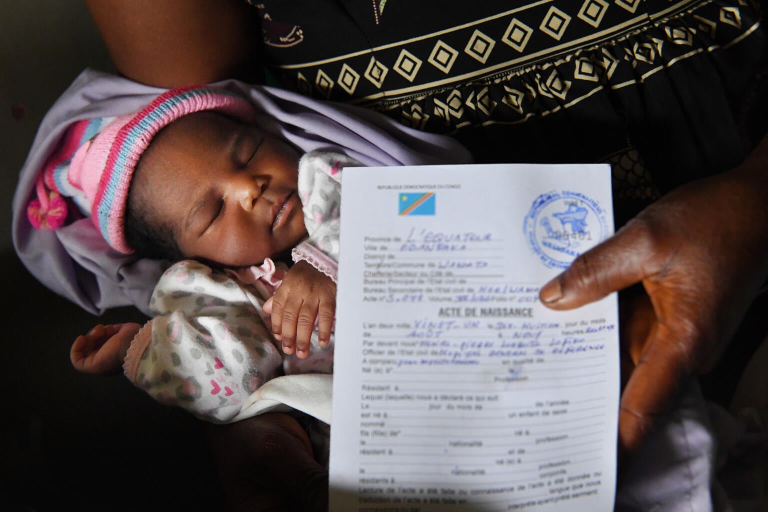 A mother holding a birth certificate in front of her child. 