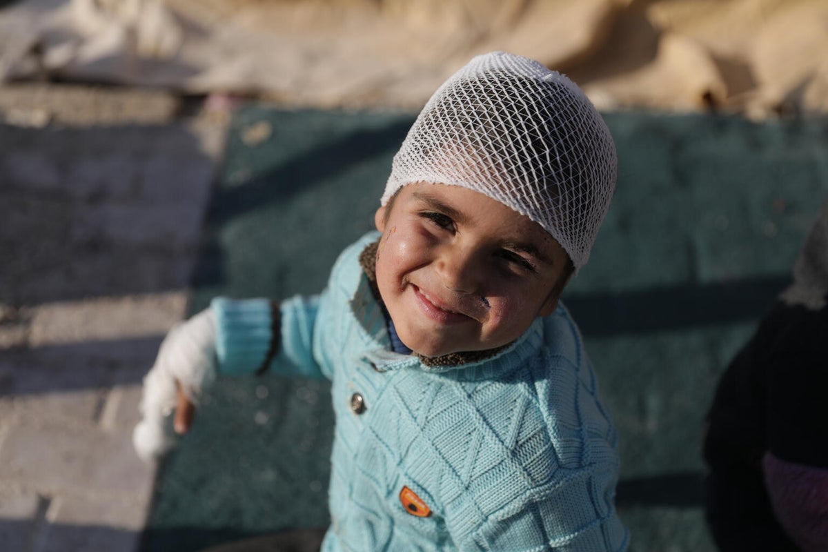 Syrian boy who was injured during the earthquake sits smiling at the camera.