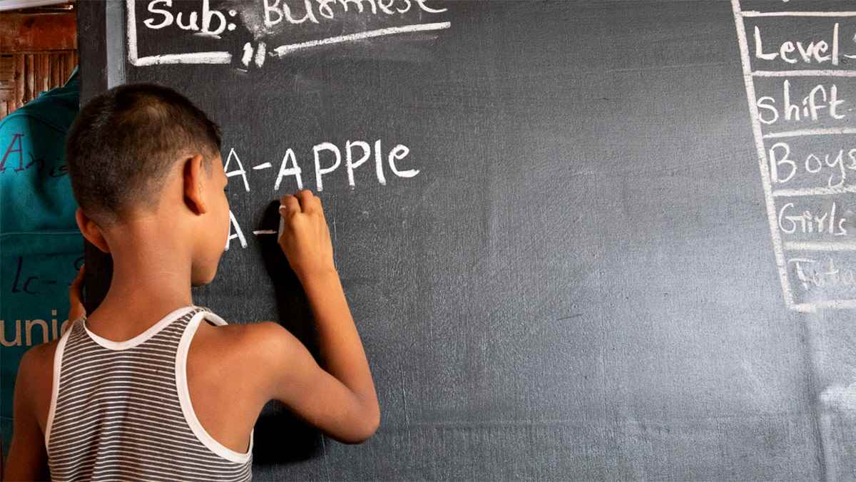A young boy writes on a chalkboard at a UNICEF-supported learning centre