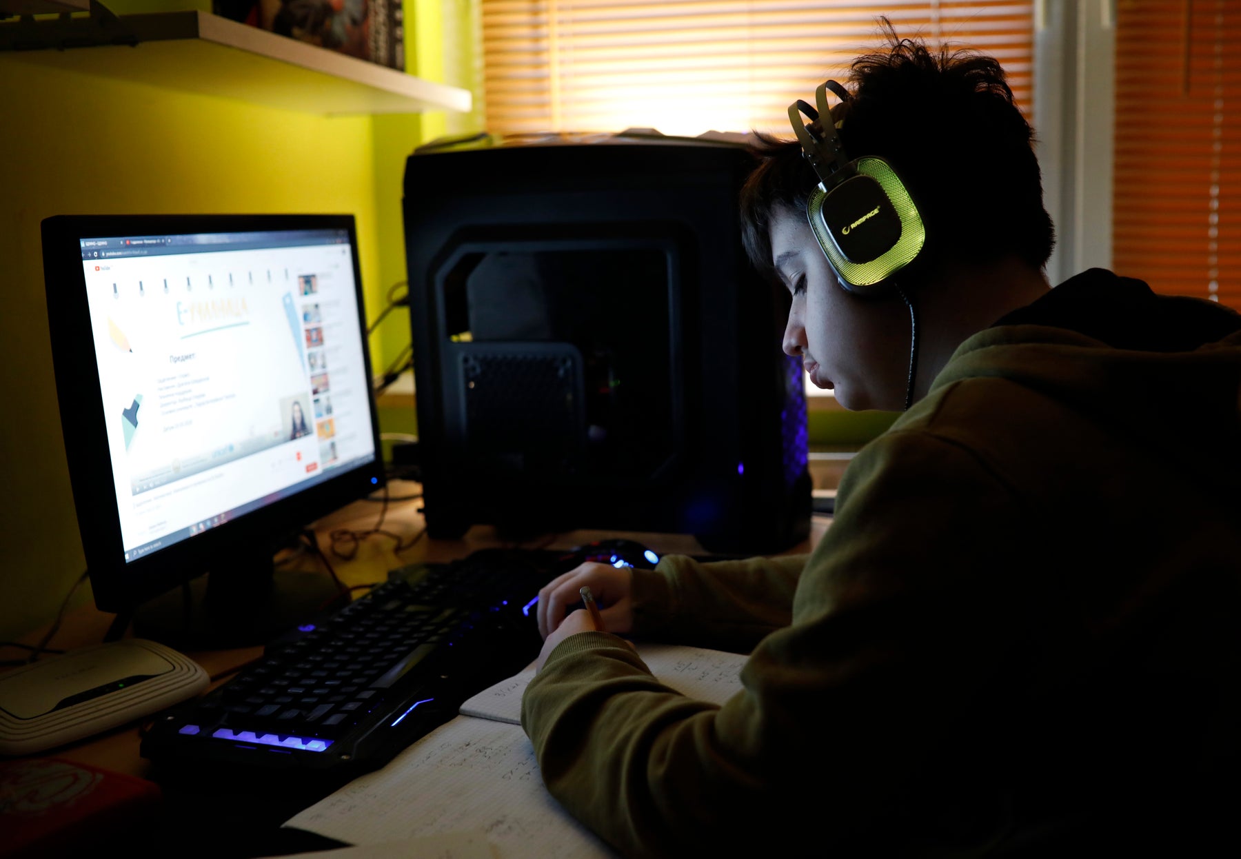Teen boy sits at computer with headphones on