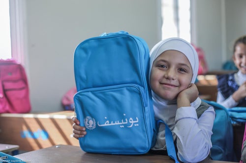 Child with UNICEF school bag smiling at camera