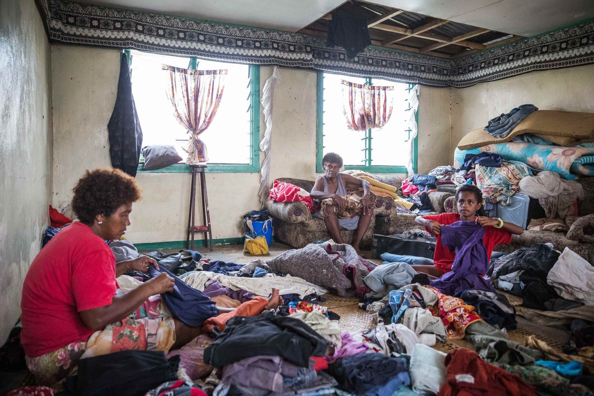 Here 10-year-old Lusiana (right) is helping her grandmother and auntie sort through and fold clothes for her family at Rakiraki village, Fiji.