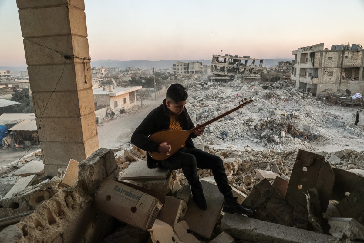 Boy plays music with a view of ruins in Syria