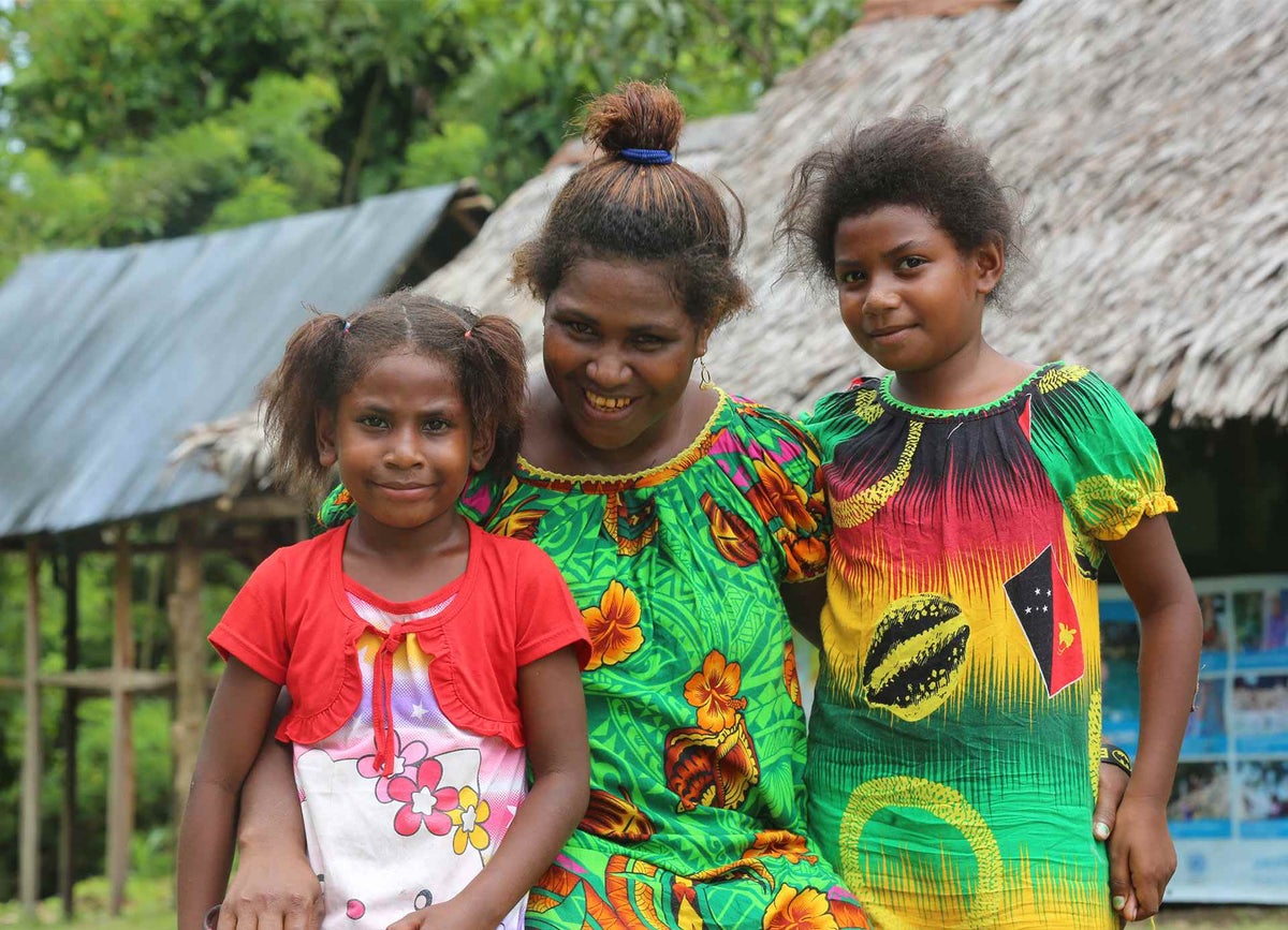 Jacklyn with her daughters, Estherlyn, six, and Roberta, eight, outside an early childhood development centre supported by UNICEF in Papua New Guinea