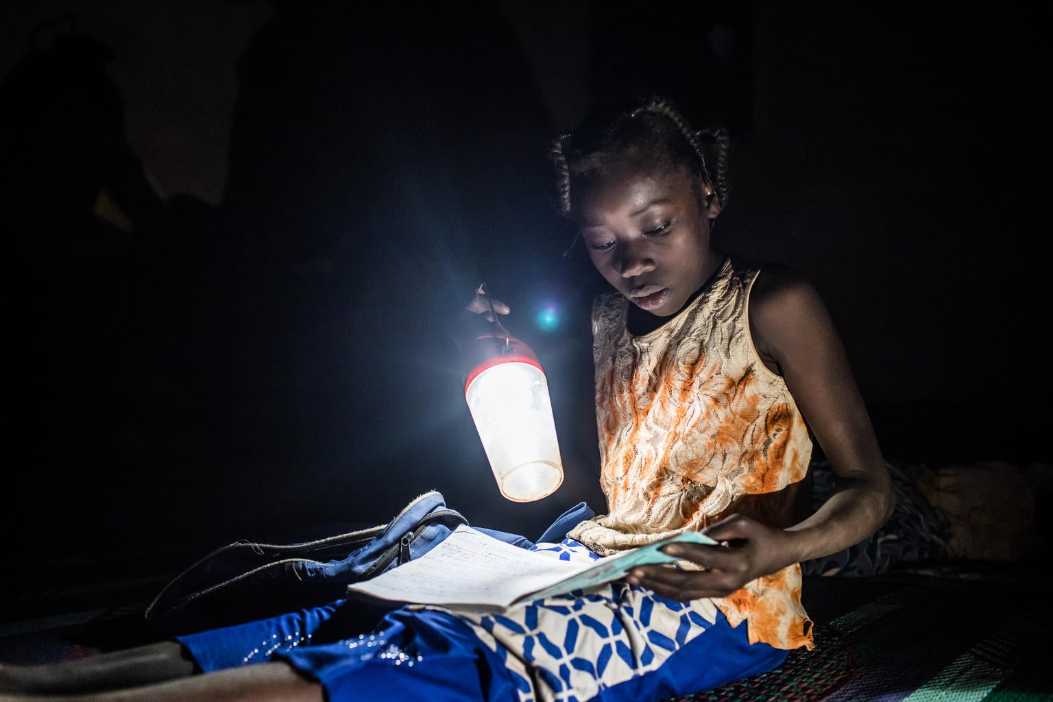 Nabyla, 13, studies at night with a handheld light in her family’s temporary home in Kaya