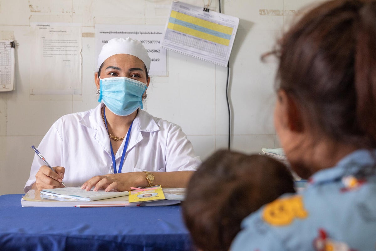 A healthcare worker in Cambodia talks to a mother and her child about the results of their health and nutrition assessment. 