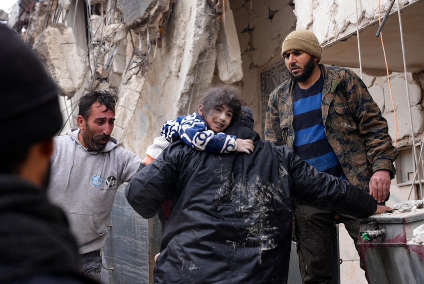 People gather around collapsed buildings as rescue teams look for survivors following an earthquake in the government-held Syrian city of Aleppo.