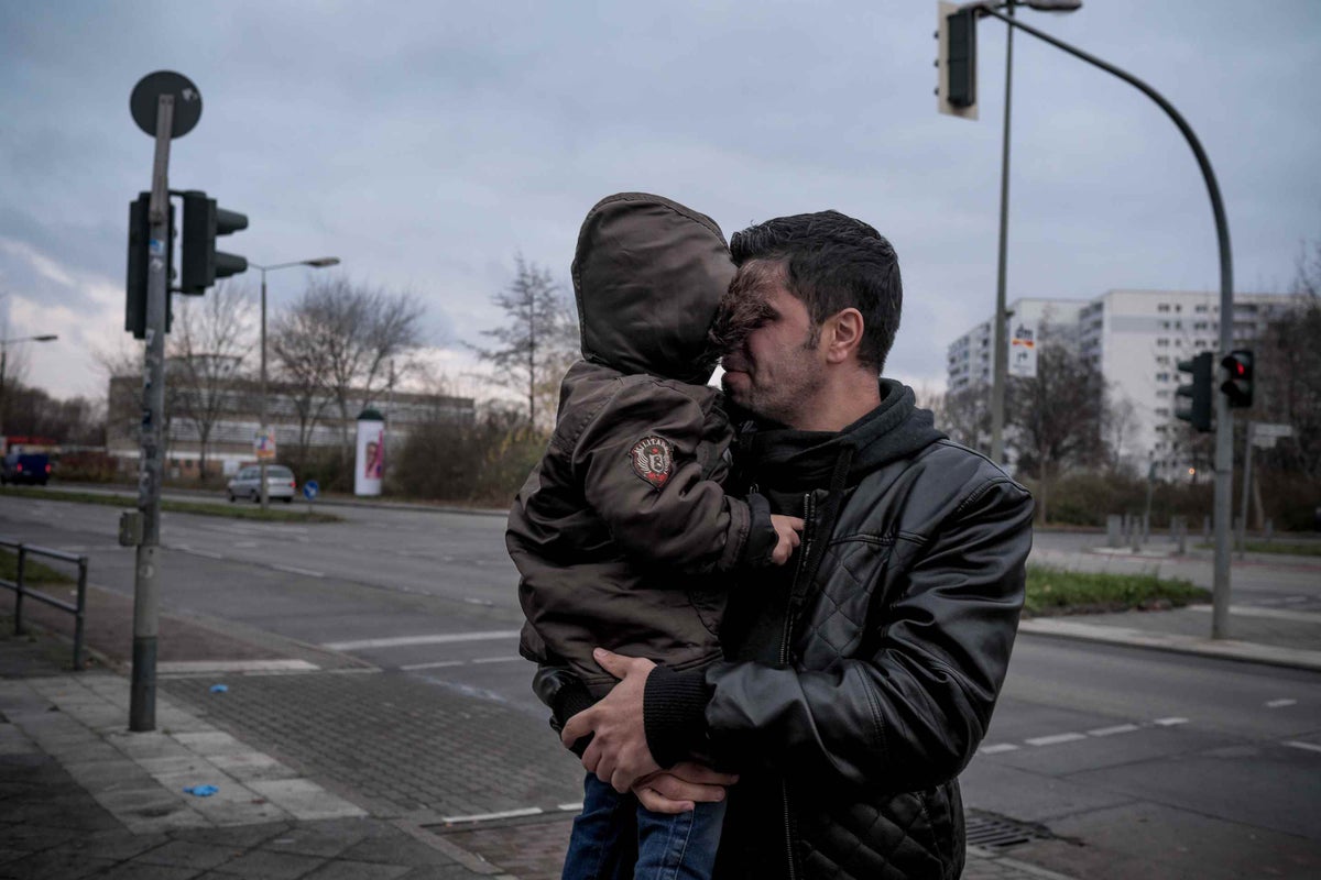 Khalid, 33, holds his youngest son Karam, 4, outside an emergency shelter at the Jane Adams School on the southern edge of Berlin