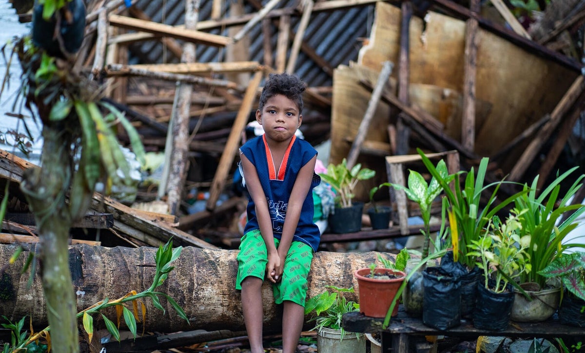 Eight-year-old Mark sits in front of his home, which was destroyed when Cyclone Rai tore through communities in the Philippines in early 2022. 