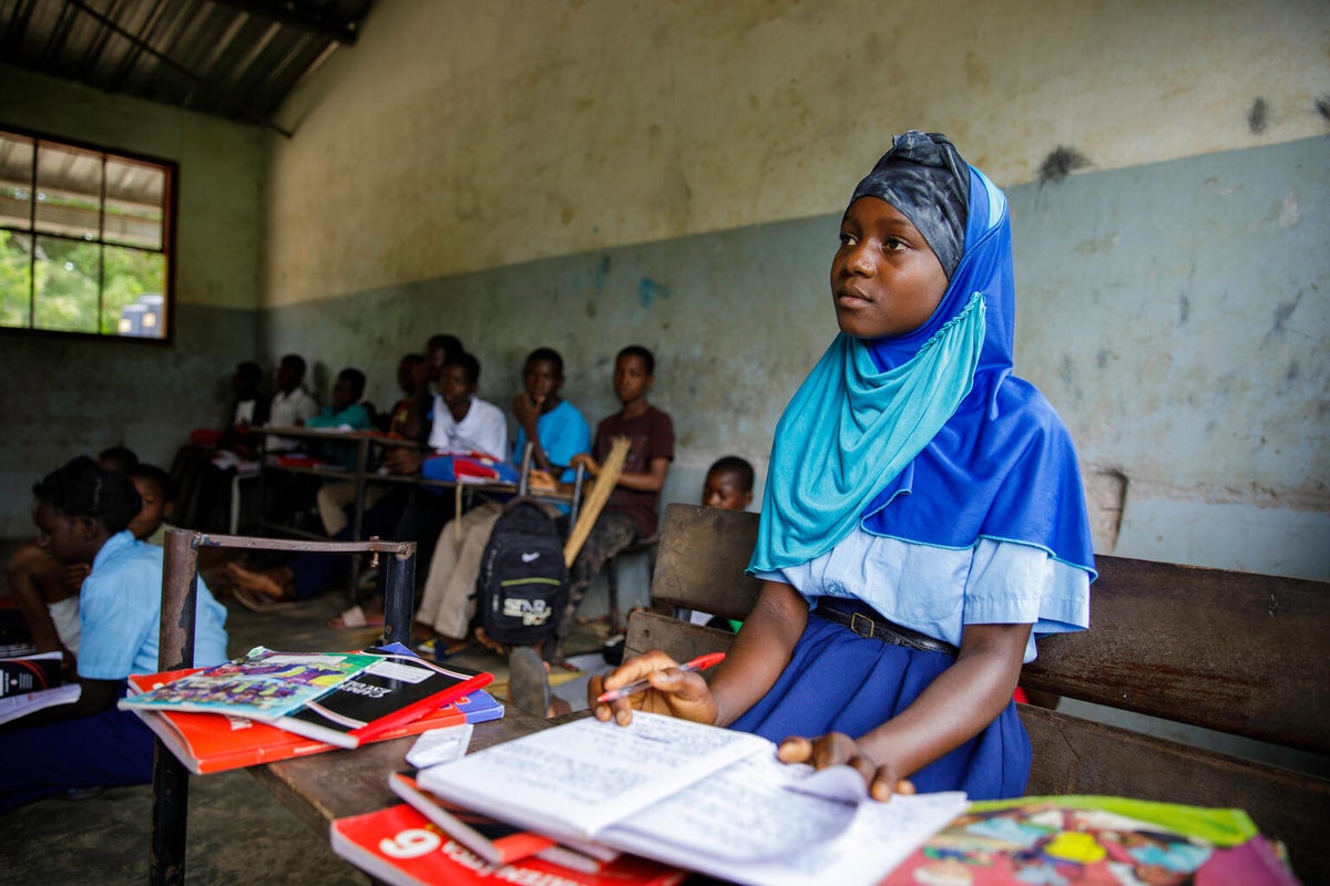 A young girl sits in her classroom.