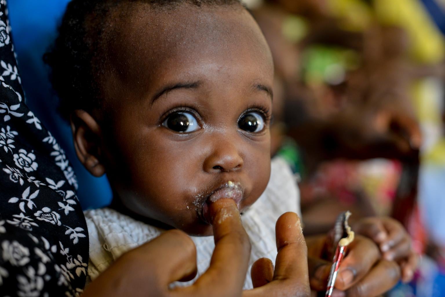 a woman feeds her infant from a sachet of ready-to-use therapeutic food
