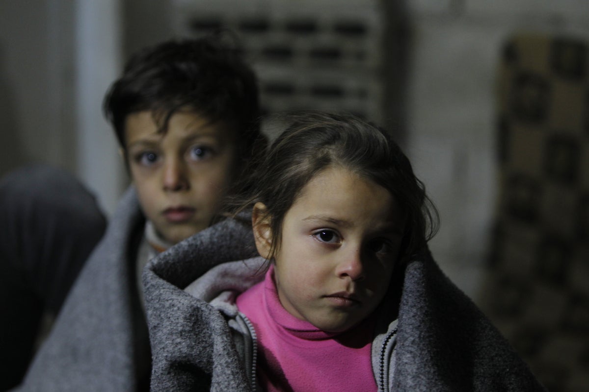 A boy and a girl look at a camera. They look sad.