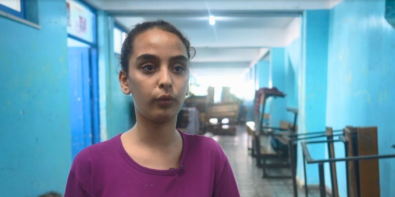 Child standing inside a school where her family is sheltering from the Gaza crisis