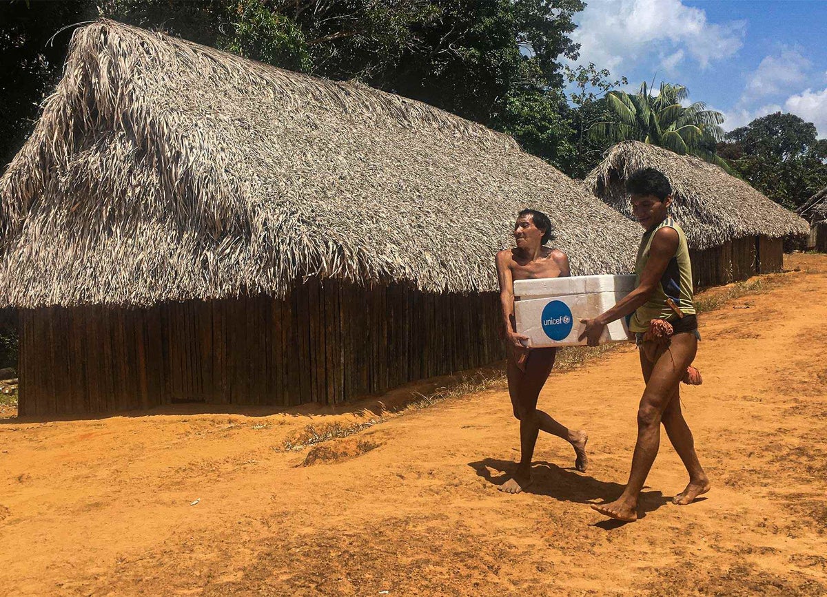 UNICEF staff ride in a “curiara” dugout canoe to visit the family homes of the Hoti ethnic group