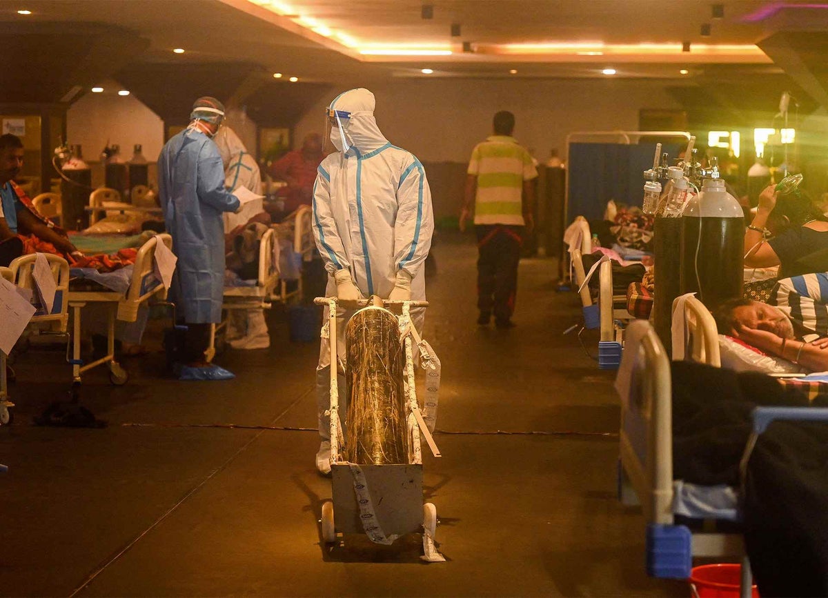 Health workers wearing personal protective equipment attend to coronavirus positive patients inside a banquet hall temporarily converted into a covid care centre in New Delhi, India. 