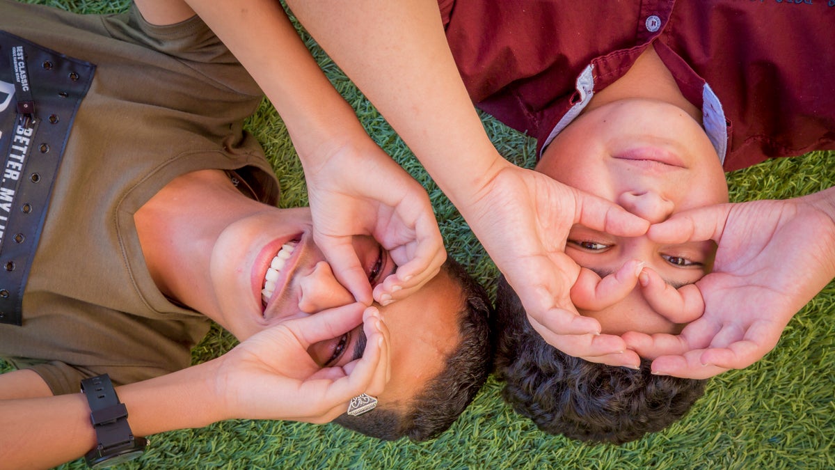 Two boys smiling with hands as glasses around their eyes.