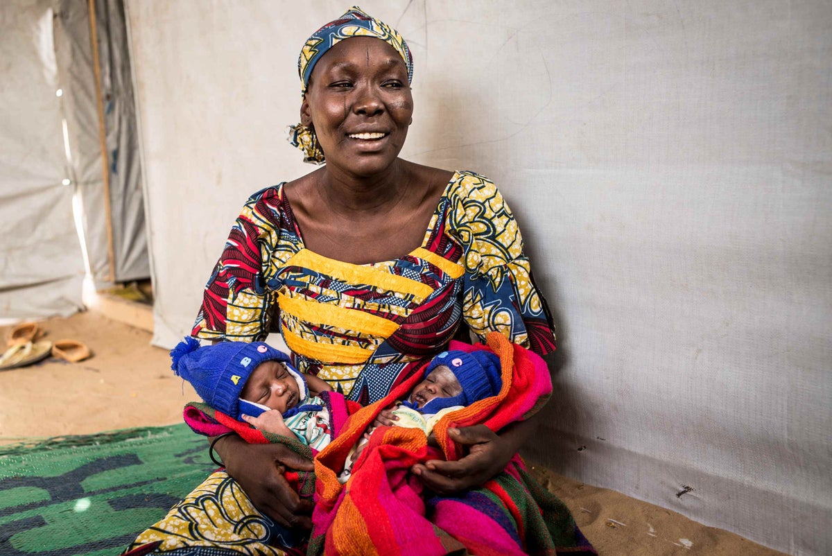 inta Mahamadou cradles her twin son and daughter inside her family’s tent shelter at the Dar es Salam refugee camp