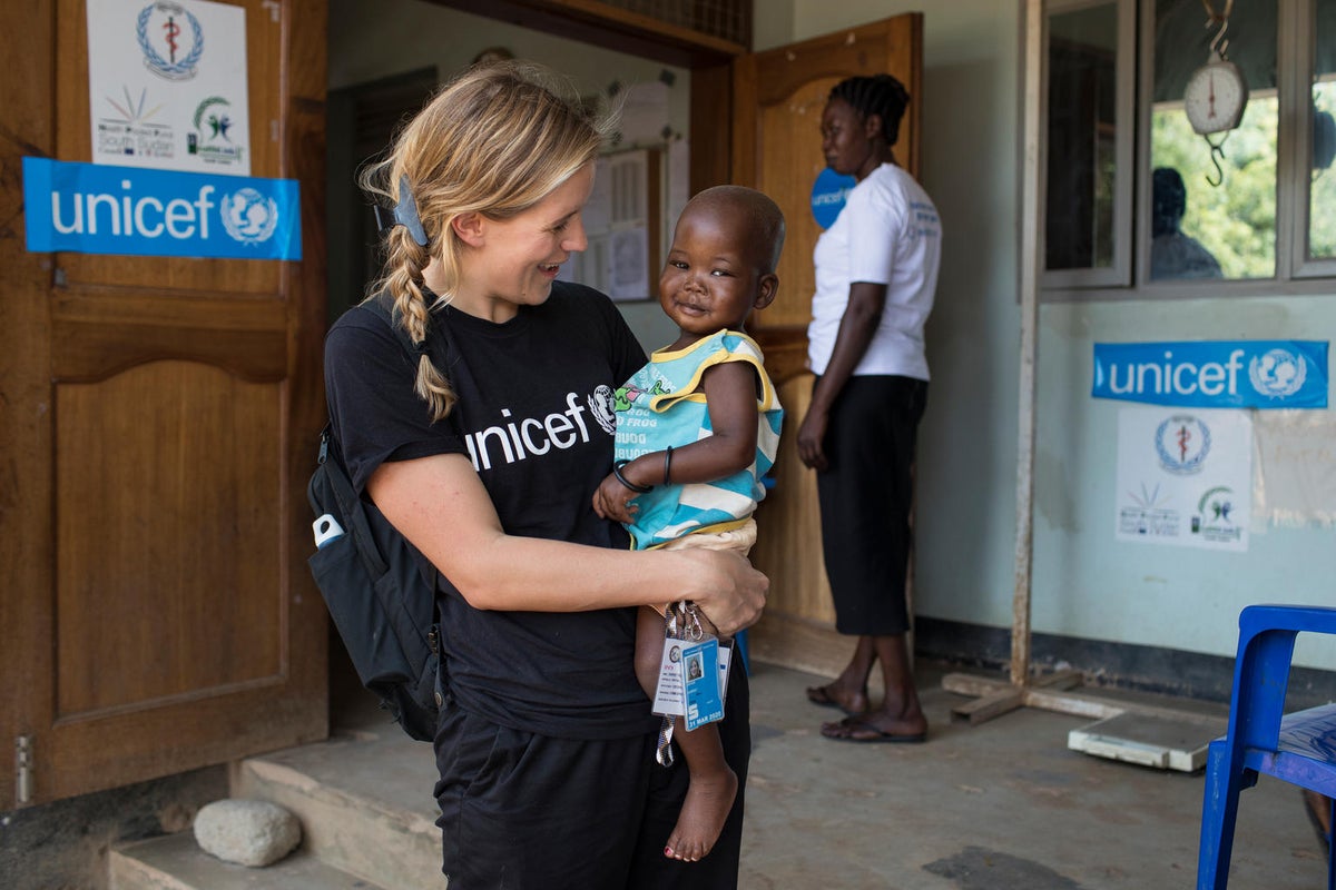 A woman with a UNICEF t-shirt is holding a baby