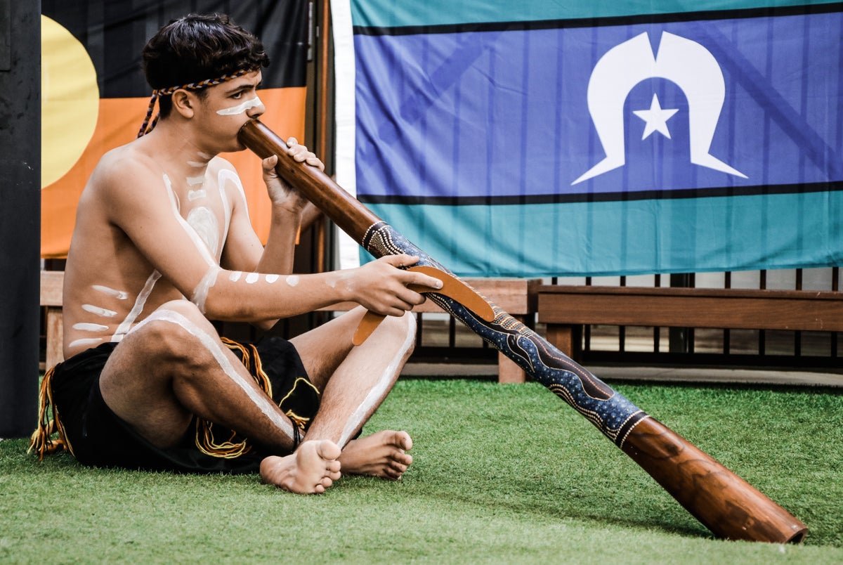 A young man playing the didgeridoo. 