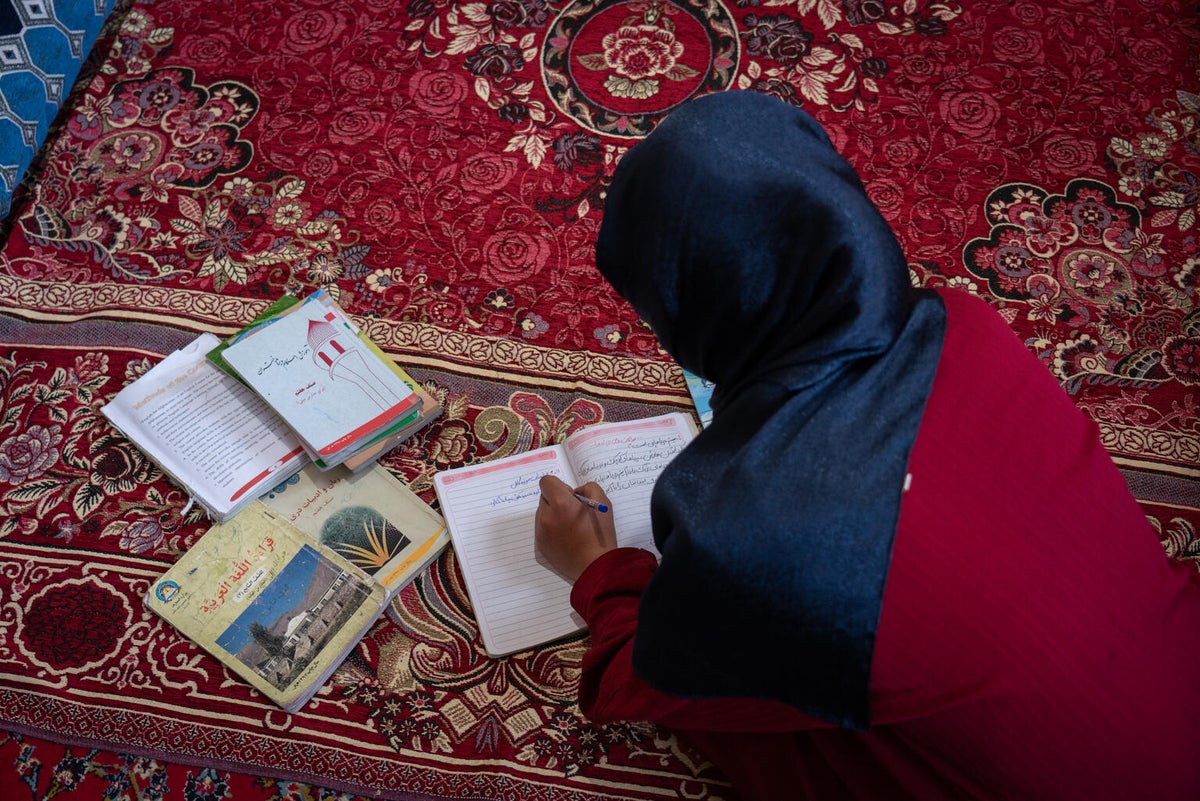 A young girl studying on the carpet at home.