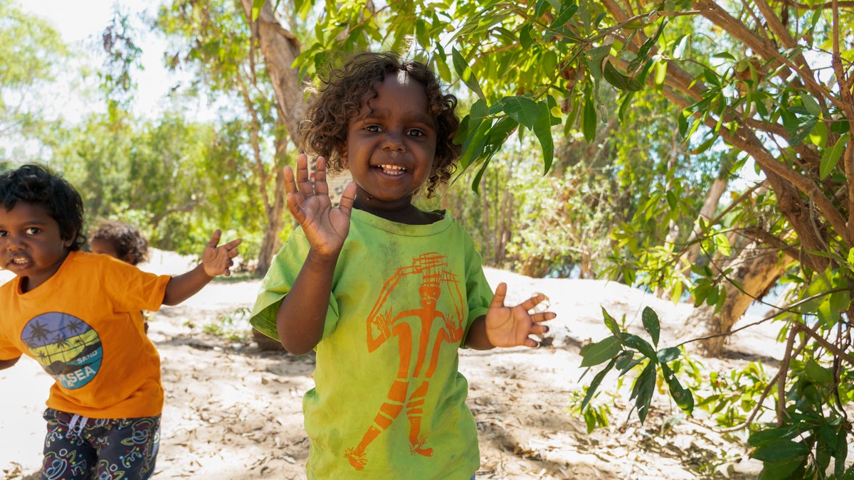 A young child waves at the camera. 