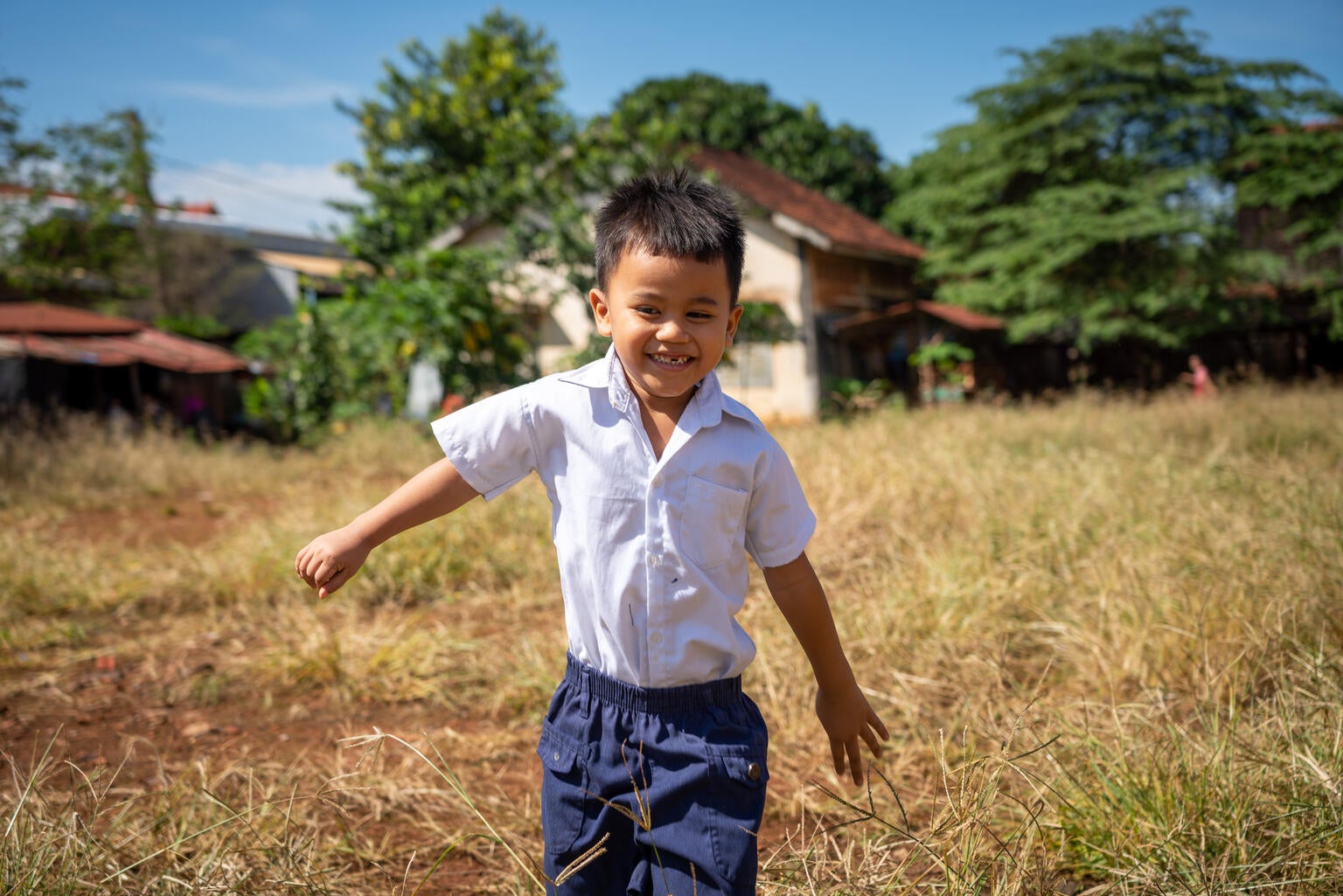 A young child running on a field. He is smiling.