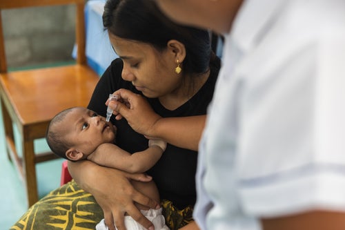 An infant receives an oral vaccination in a health centre in Kiribati.