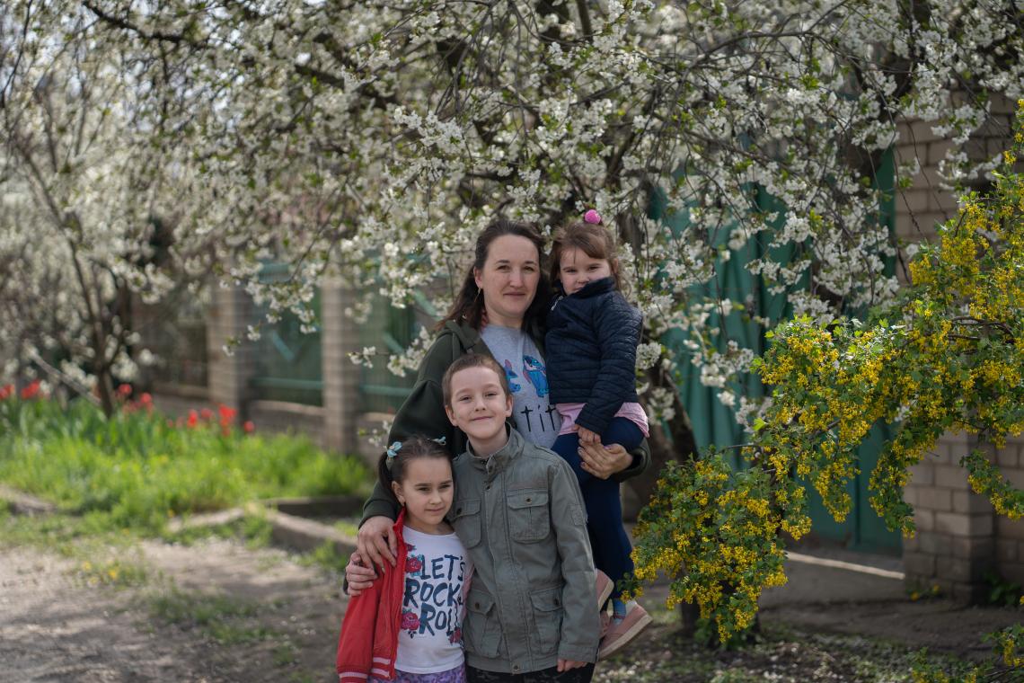 A mother with her three children standing in their garden. 