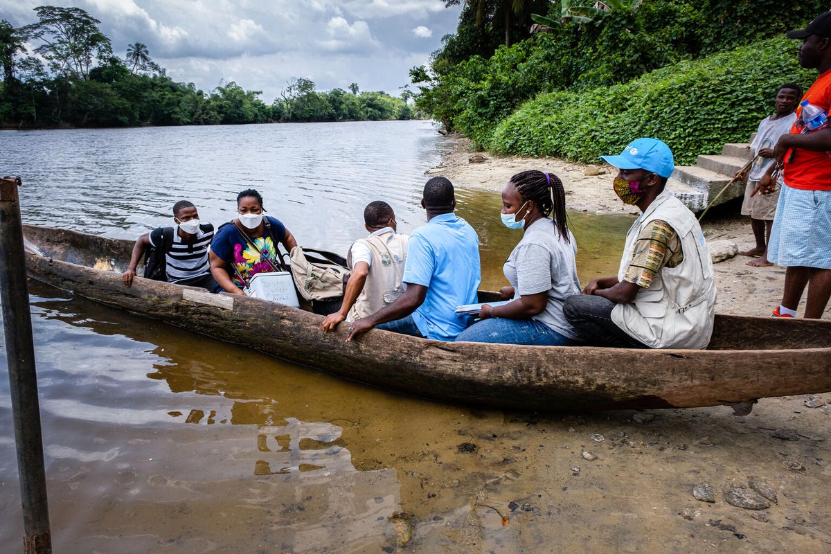 Health workers take a boat across the St. John river to vaccinate children against polio in a village in Liberia.  