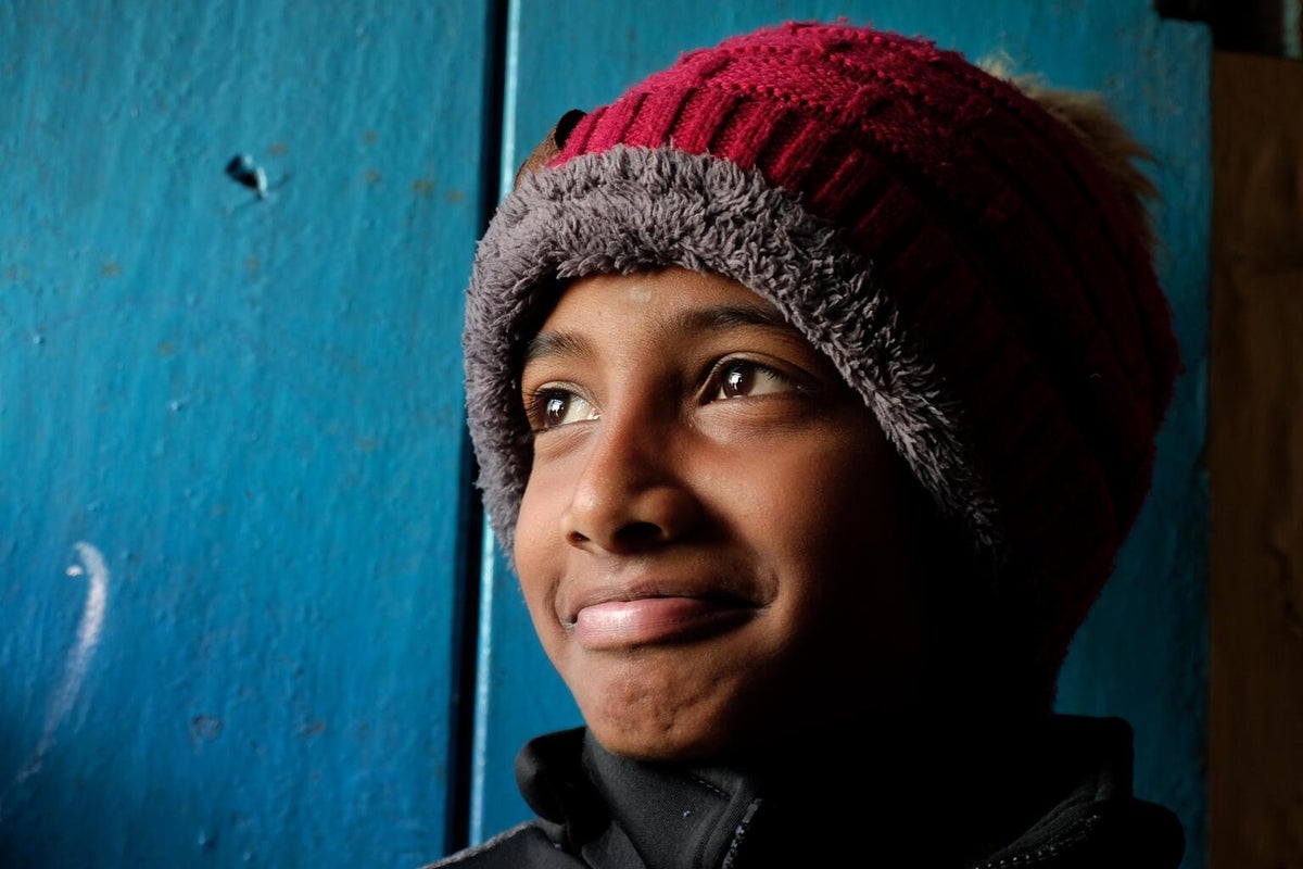 A boy smiling. He is wearing a beanie.