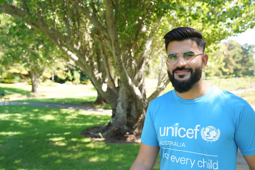 Dr. Zameer Gill at a park in a UNICEF shirt and smiling at the camera