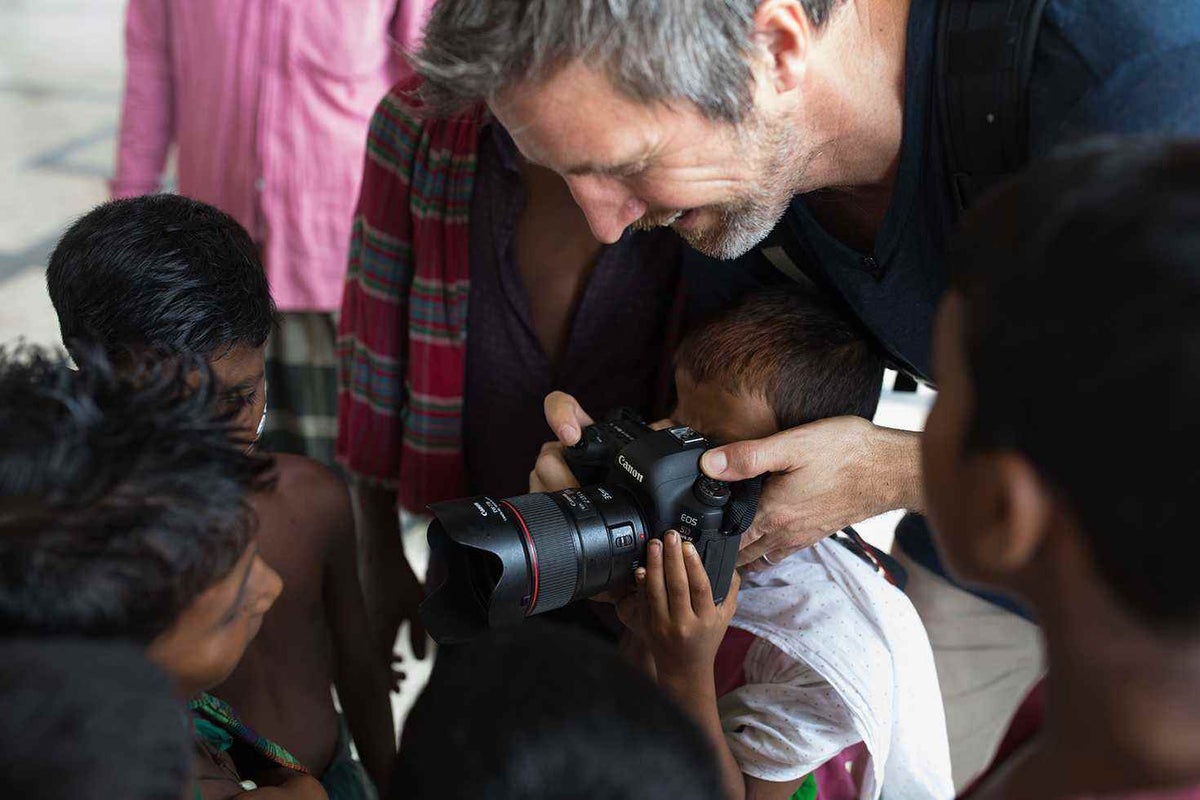Simon shows children what it's like to look through a cameras lens. These children live around the old train station in Dhaka, Bangladesh.