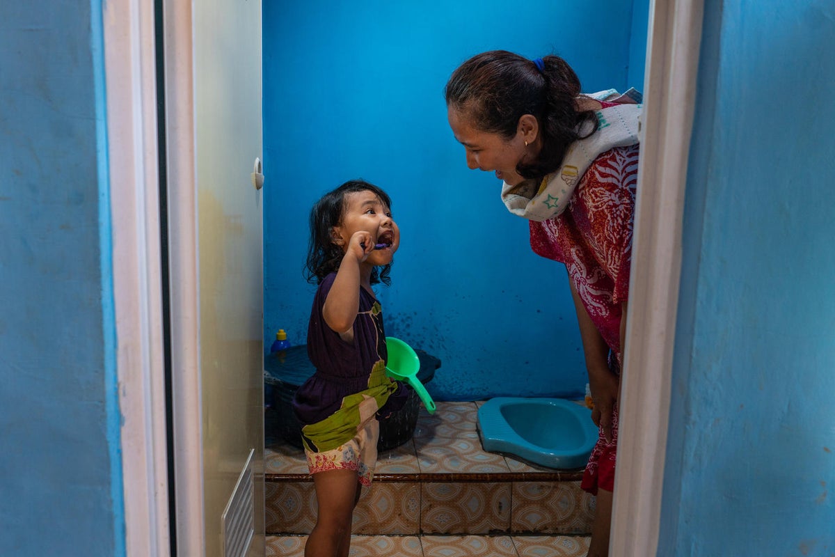 A young girl is showing her mum how she brushes her teeth.