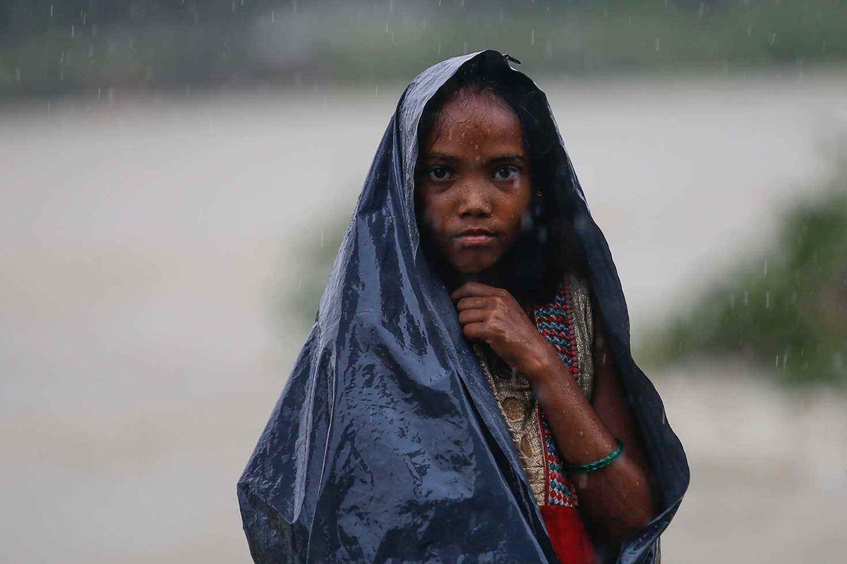 A girl uses plastic sheets as makeshift rain cover.