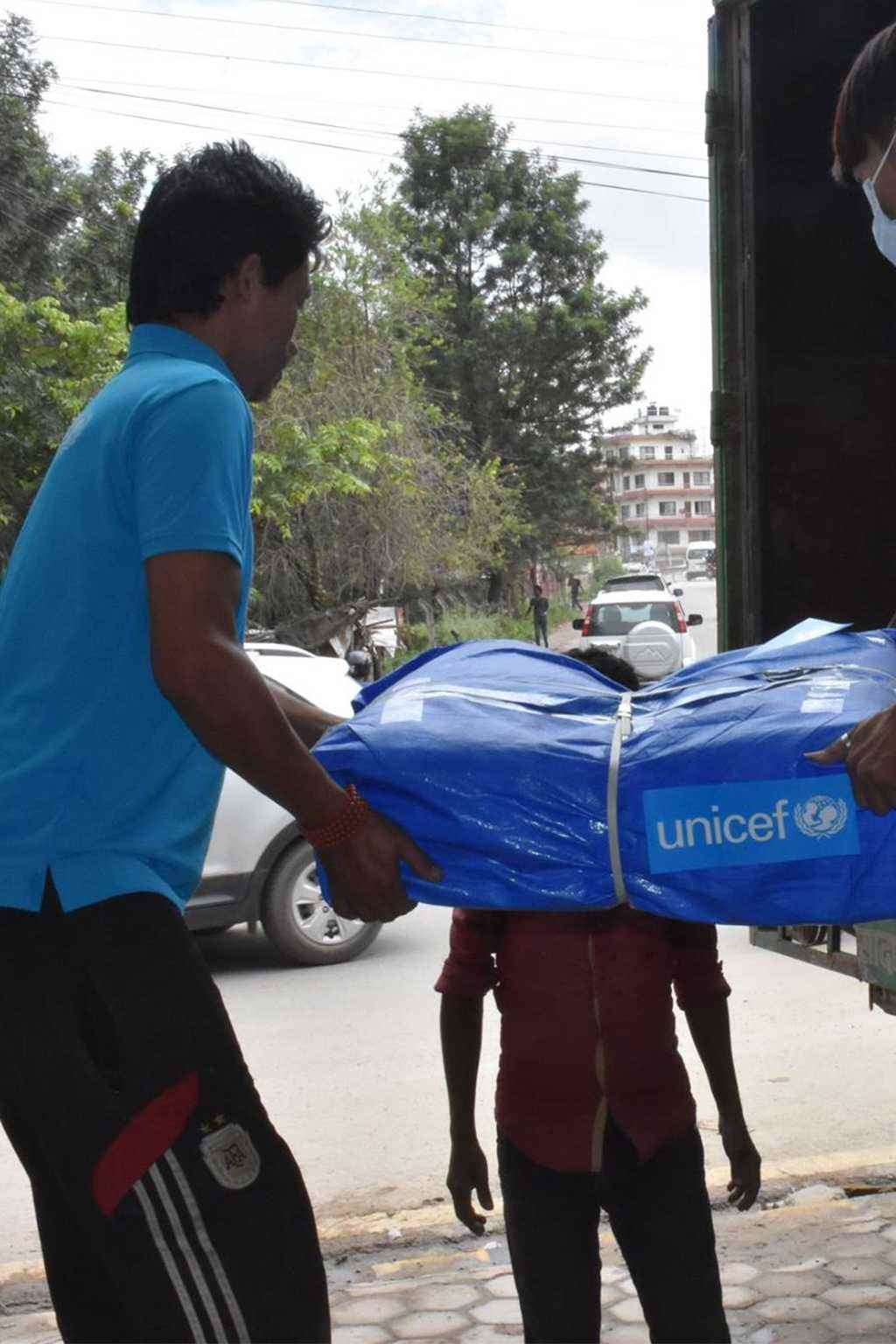 Tarpaulins are loaded onto trucks from a UNICEF warehouse.