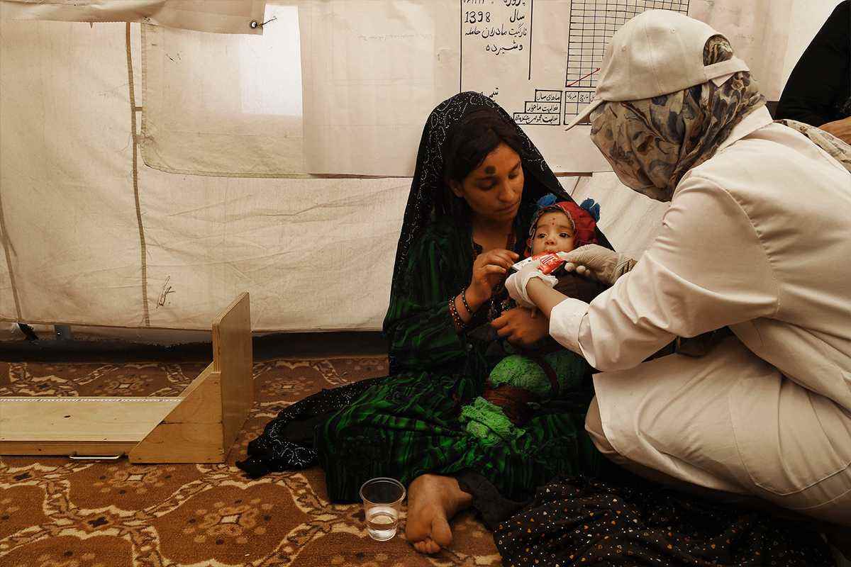 Medical staff showing mother how to feed her baby 